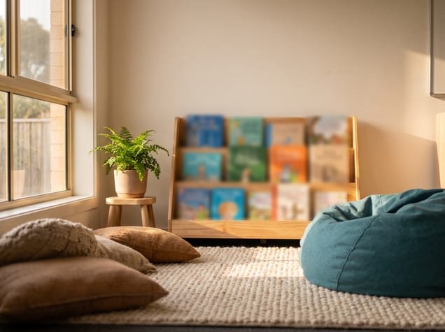 A reading corner with floor cushions, a rug and a beanbag